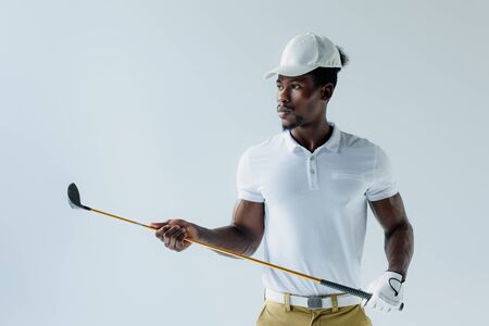 serious african american sportsman holding golf club isolated on greyの写真素材