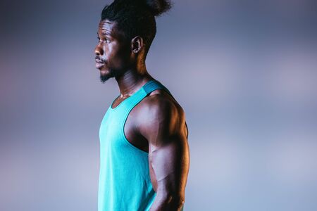 handsome, muscular african american sportsman looking away on grey background with lighting