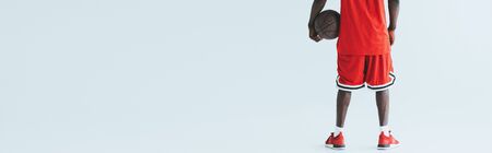 cropped view of african american basketball player holding ball on grey background, panoramic shotの写真素材
