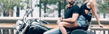 cropped view of young couple of bikers on black motorcycle on road, panoramic shotの写真素材