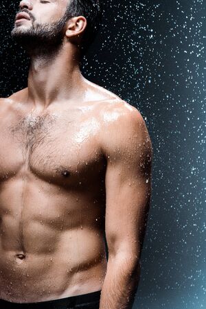 cropped view of shirtless sexy man standing under raindrops on blackの写真素材