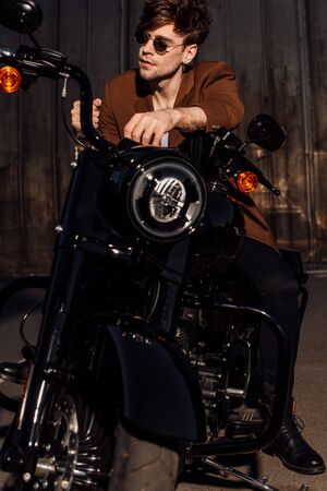 front view of man in sunglasses sitting on motorcycle and looking awayの写真素材