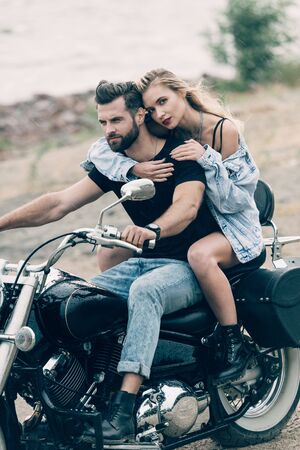young couple of bikers hugging on black motorcycle at sandy beachの写真素材