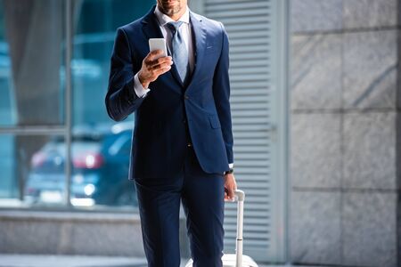 cropped view of man in suit using smartphone outsideの写真素材