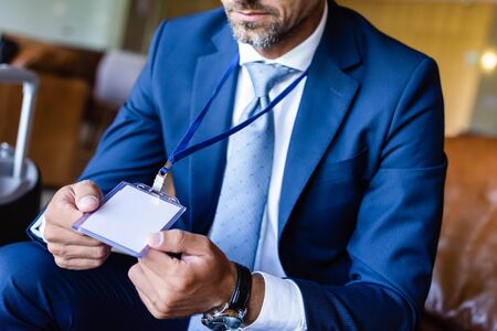 cropped view of man in formal wear holding badge with copy space