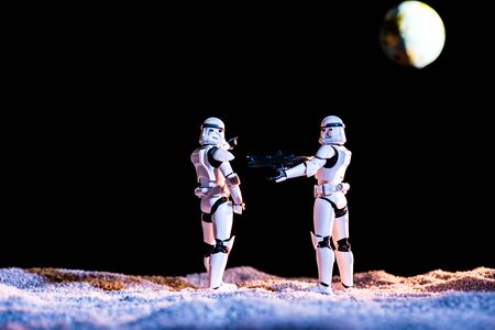 KYIV, UKRAINE - MAY 25, 2019: white imperial stormtroopers with gun on black background with planet Earthのeditorial素材
