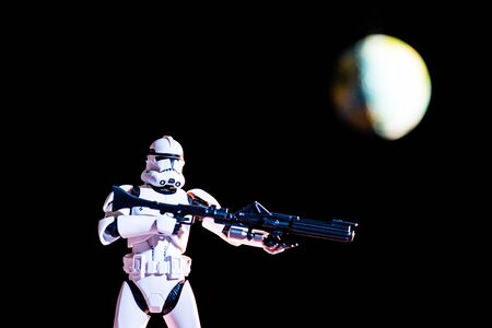 KYIV, UKRAINE - MAY 25, 2019: white imperial stormtrooper figure with gun on black background with blurred planet Earthのeditorial素材
