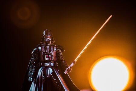 KYIV, UKRAINE - MAY 25, 2019: Darth Vader figurine with lightsaber on black background with shining sunのeditorial素材