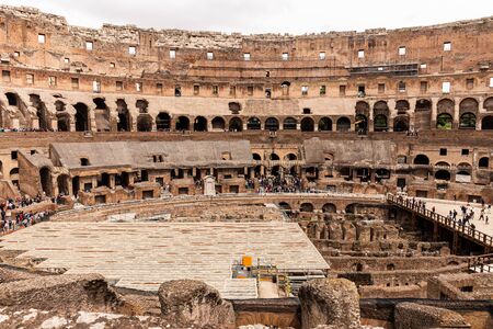 ROME, ITALY - JUNE 28, 2019: ruins of colosseum and crowd of tourists under grey sky
