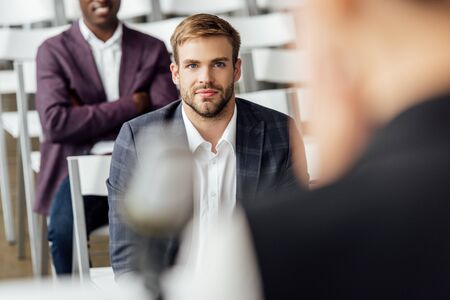selective focus of businessman in formal wear sitting during conferenceの写真素材
