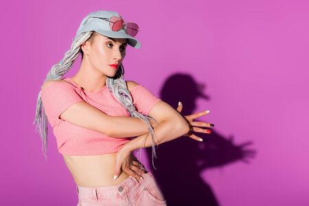 beautiful stylish girl with dreadlocks posing and Gesturing on purple