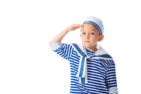 serious preschooler child in sailor costume saluting and looking at camera isolated on whiteの写真素材