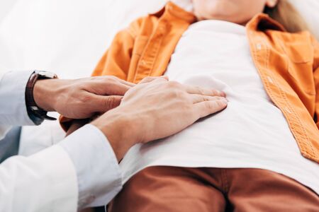 cropped view of pediatrist in white coat examining child in clinicの写真素材