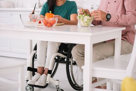 partial view of disabled woman in wheelchair cooking together with boyfriend in kitchen