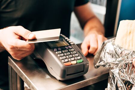 cropped view of man with doner kebab using credit cardの写真素材