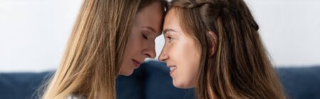 panoramic shot of two lesbians touching foreheads at home