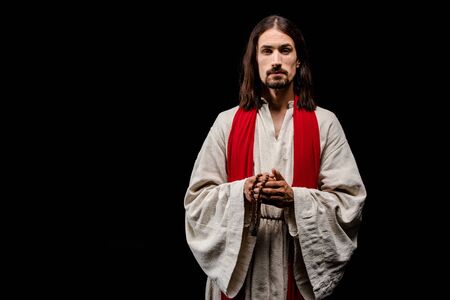 handsome man holding rosary beads isolated on blackの写真素材