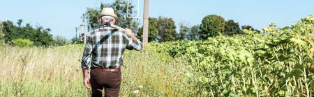 panoramic shot of self-employed man holding rack near green fieldの写真素材