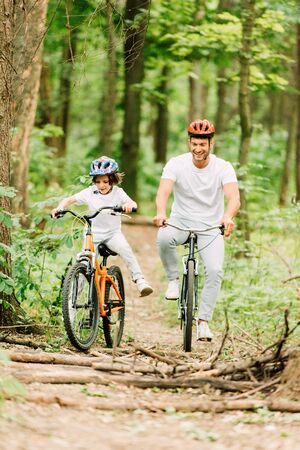 full length view od father and son riding above fallen brunches