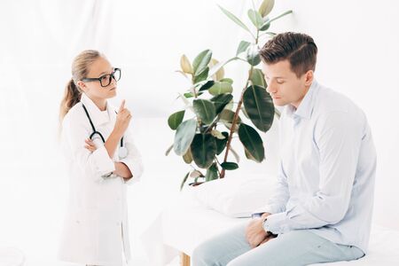 child in glasses and doctor costume examining patient