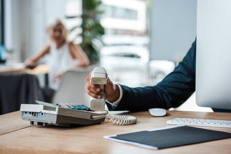 cropped view of businessman holding retro phone in officeの写真素材