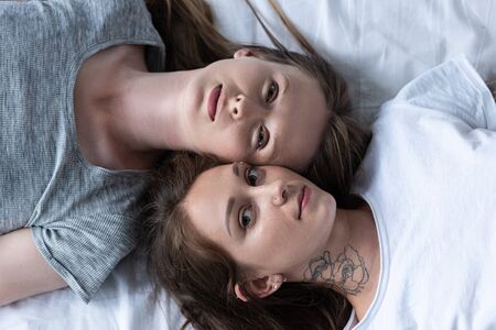 top view of two lesbians lying in bed togetherの写真素材