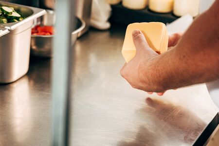 cropped view of cook holding cheese at workplaceの写真素材