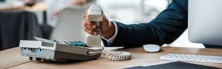 panoramic shot of businessman holding retro phone in officeの写真素材