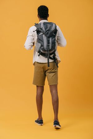 back view of african american man standing with backpack on orangeの写真素材