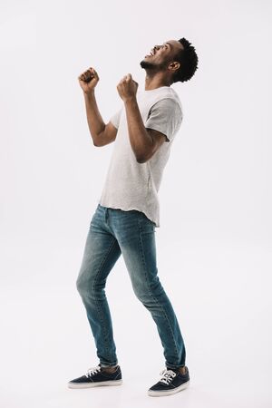 excited african american man gesturing while celebrating triumph isolated on whiteの写真素材