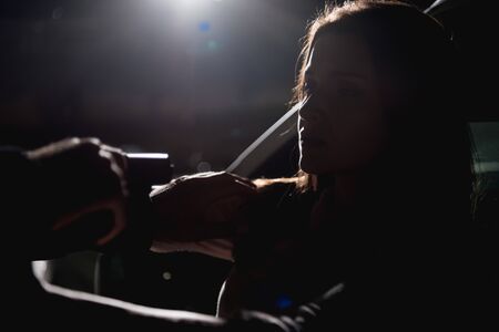 thief pointing gun at woman sitting in car at night with back lightの写真素材