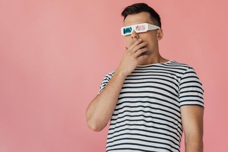 surprised young man in 3d glasses and striped t-shirt looking away isolated on pinkの写真素材