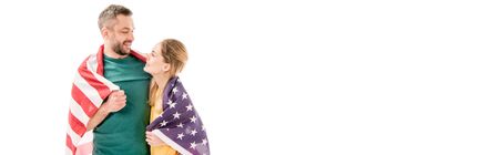 panoramic shot of smiling couple with american flag embracing and looking at each other isolated on whiteの写真素材
