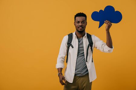 handsome african american man holding blue thought bubble isolated on orange