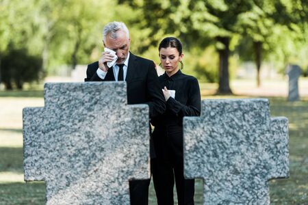 selective focus of upset man crying near woman on funeral