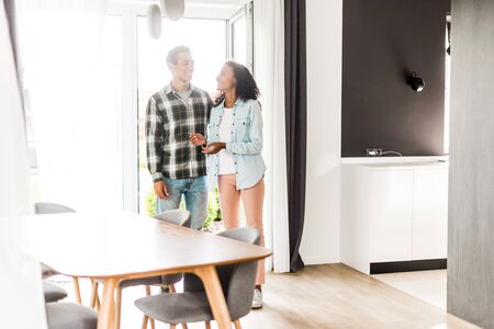 full length view of african american husband and wife walking into house while looking at each otherの写真素材