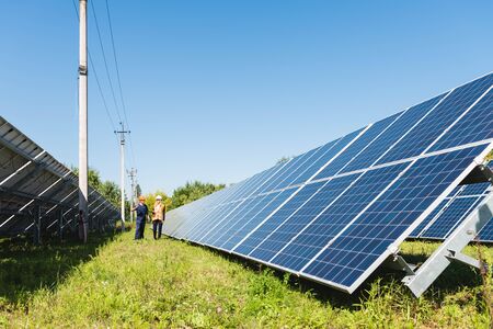 engineer and businesswoman walking near solar energy batteries