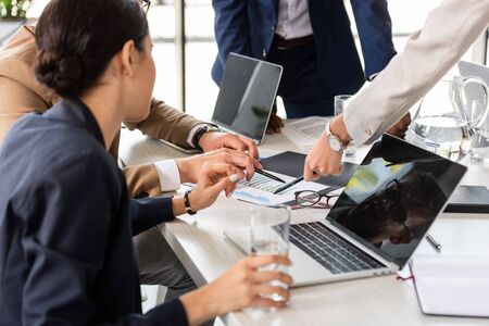 partial view of businesspeople at table during conference in officeの写真素材