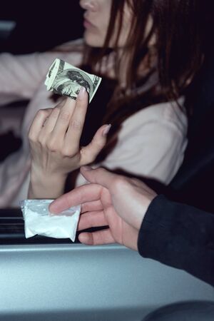 cropped view of woman in car with dollar banknotes buying drugs from thugの写真素材