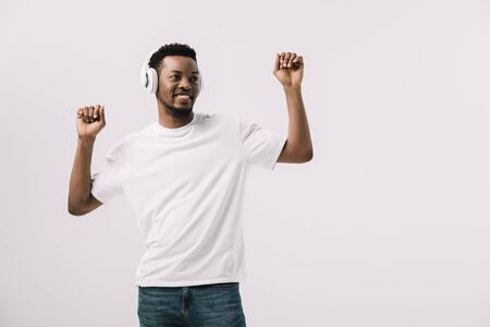 positive african american man listening music in headphones and gesturing isolated on whiteの写真素材
