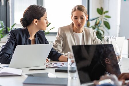two businesswomen in formal wear at table in officeの写真素材