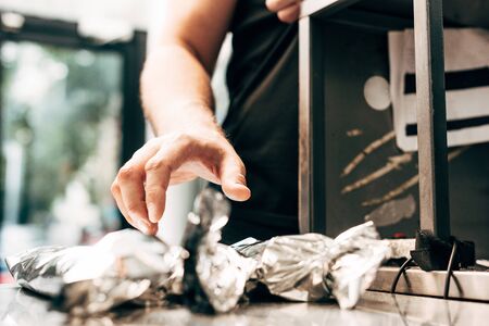 cropped view of man and doner kebabs in aluminium foilの写真素材