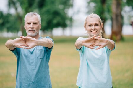 smiling mature sportsman and sportswoman warming our in parkの写真素材