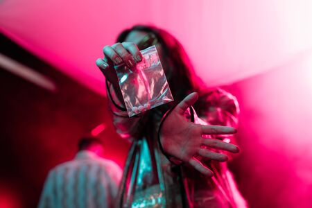 girl holding plastic zipper bag with drugs in nightclub, selective focus