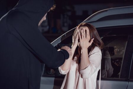 thief attacking woman covering face near car at nightの写真素材