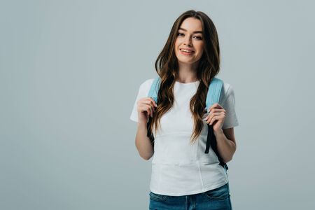 pretty smiling girl with blue backpack isolated on grey