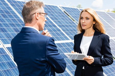 businessman and attractive businesswoman talking and using digital tablet