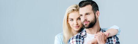 panoramic shot of beautiful young couple hugging isolated on grey