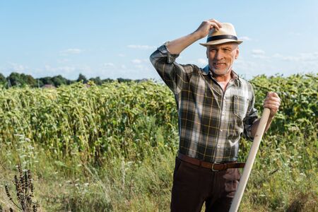 happy self-employed man holding rack near green field