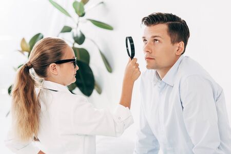 child in doctor costume examining patient with magnifier